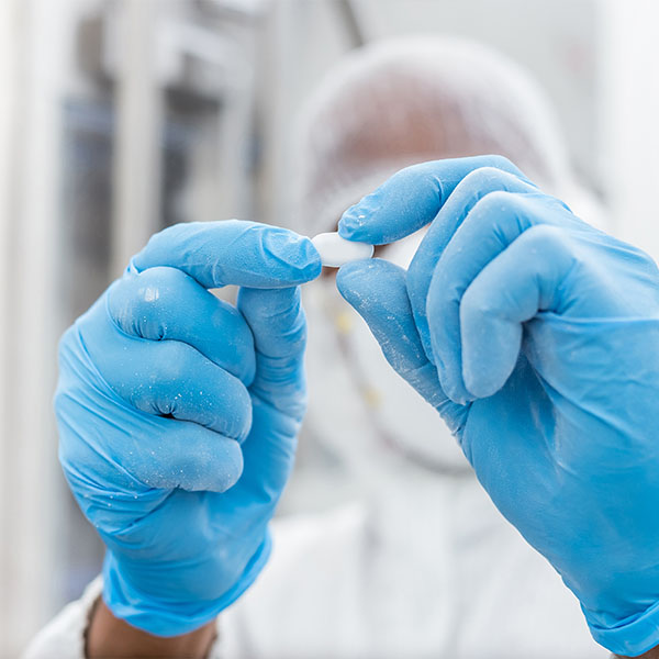 A scientist examining a white pill.